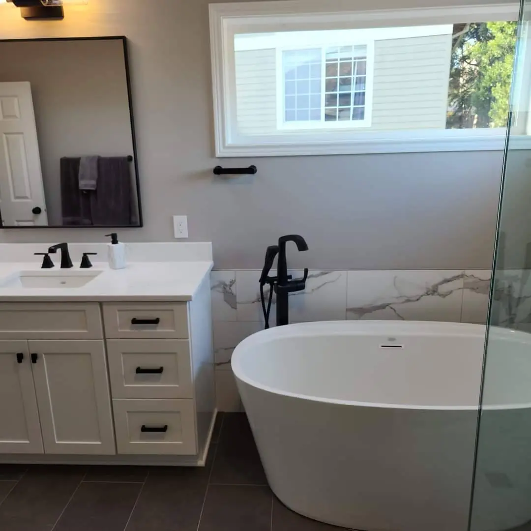 Master bath vanity with freestanding tub and marble wainscoting
