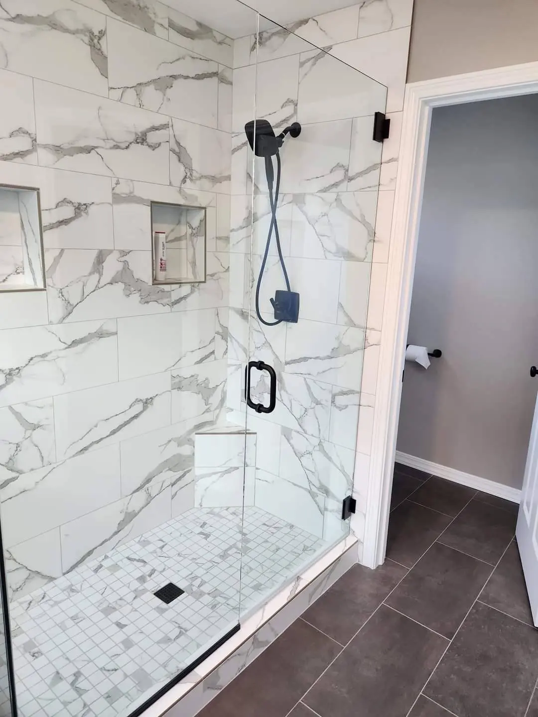 Frameless glass shower with marble tile and built-in niche