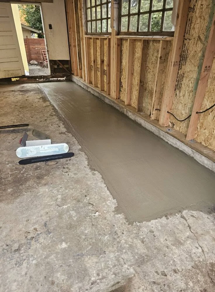 Freshly poured concrete slab along garage foundation